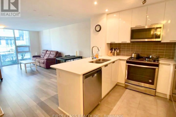 View from kitchen island showing living area with sofa and dining table. - 117 - 5033 Four Springs Avenue, Mississauga