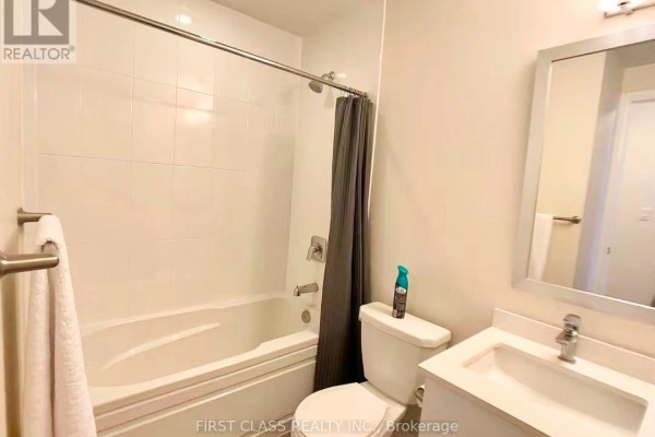 Modern bathroom with white tiled walls, bathtub, toilet, and vanity with sink. - 117 - 5033 Four Springs Avenue, Mississauga