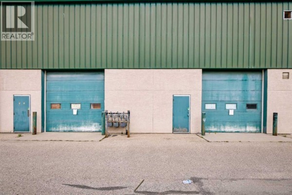 Rear exterior of a commercial building with green metal siding and garage doors. - 117 & 119, 3825 34 Street Ne, Calgary