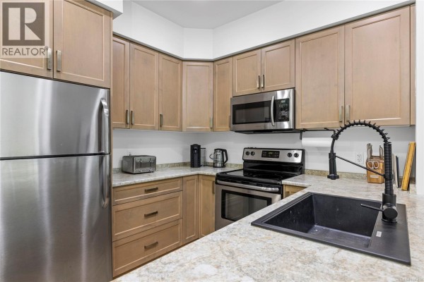Kitchen featuring light wood cabinets, stainless steel appliances, and granite countertops. - 117 4960 Songbird Pl, Nanaimo