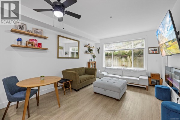 Living area with dining table, sofa, and decorative shelves. - 117 4960 Songbird Pl, Nanaimo