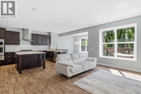 Modern kitchen with dark wood cabinets, stainless steel appliances, quartz countertops, and a large island. - 117 Auburn Glen Drive Se, Calgary