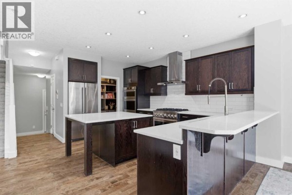 Close-up of a professional gas range, white subway tile backsplash, and dark wood cabinetry in the kitchen. - 117 Auburn Glen Drive Se, Calgary
