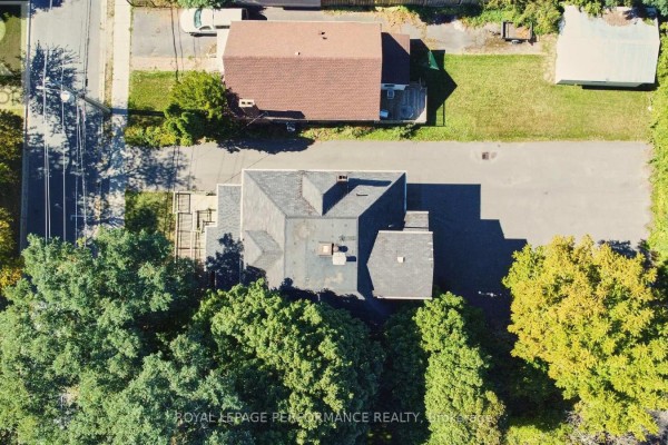 Aerial view of a grey-roofed building surrounded by lush green trees, with a neighboring property visible. - 117 First Street E, Cornwall