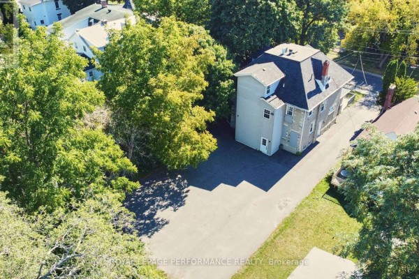 Aerial view of the grey building, asphalt parking, and surrounding trees, showing the property's layout. - 117 First Street E, Cornwall