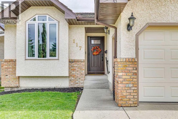 Close-up of the front entrance featuring a dark wood door with a wreath and a bay window. - 117 Hawkbury Close Nw, Calgary