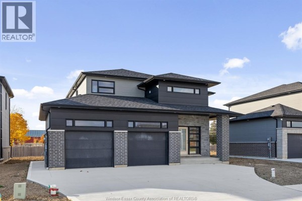 Side view of the house showcasing the gray siding and stone foundation. - 117 Hazel Crescent, Kingsville