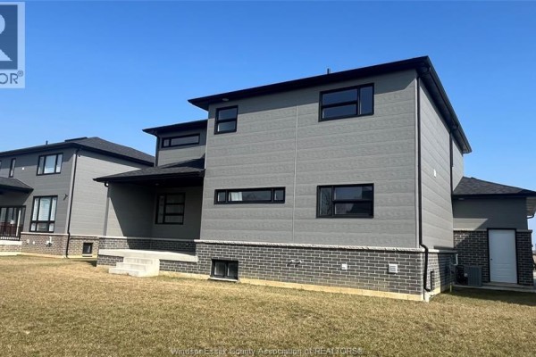 Backyard view of the home highlighting the gray siding and landscaping area. - 117 Hazel Crescent, Kingsville