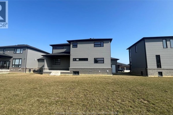 Another side view of the house with a clear sky and grassy yard. - 117 Hazel Crescent, Kingsville