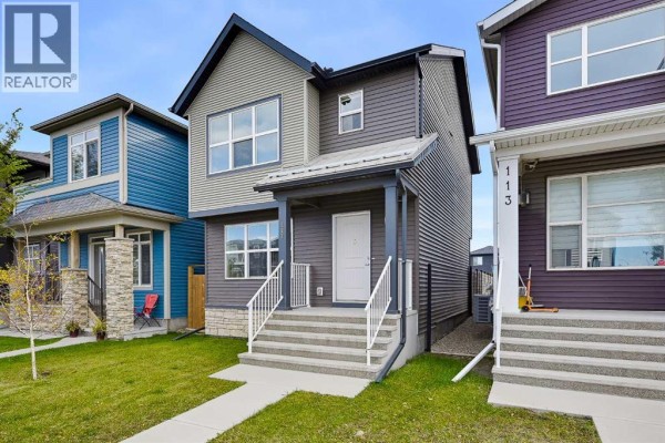 Front view of a modern house with grey and beige siding, white front door, and porch. - 117 Howse Avenue Ne, Calgary