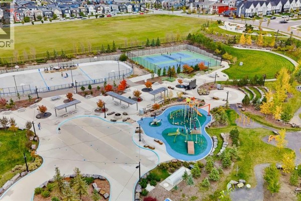 Aerial view of a park with a playground, splash pad, tennis courts, and an ice rink. - 117 Howse Avenue Ne, Calgary