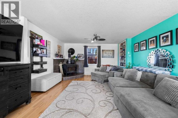 Living room with a sectional sofa, wood-burning stove, and a turquoise accent wall. - 117 James Street, Bittern Lake