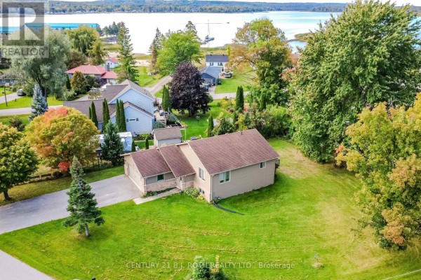 Aerial view of a beige bungalow with a large yard, surrounded by trees and other homes. - 117 Juneau Road, Tay