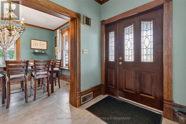 Interior view of the entryway and dining room with double wooden doors, teal walls, and wooden trim. - 117 Main Street E, South Huron