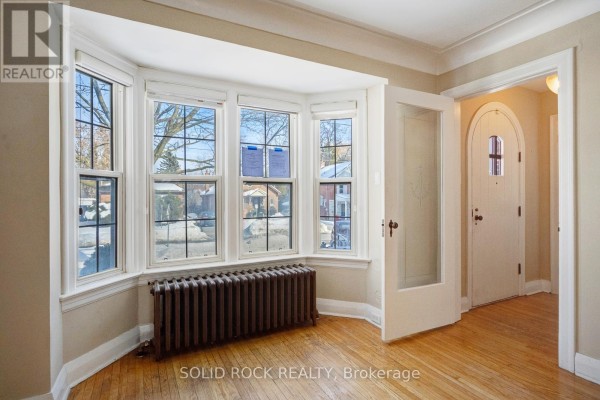 Bay window area with radiator and adjacent front door - 117 Mill Street S, Brampton