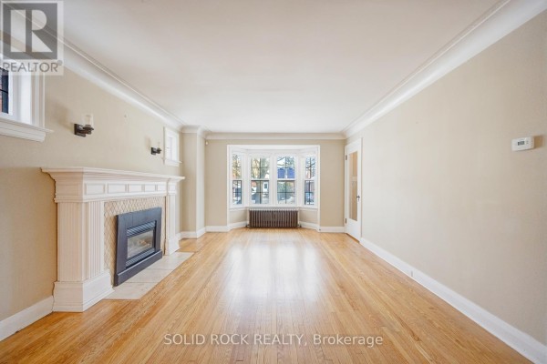 Spacious living room with hardwood floors and decorative fireplace - 117 Mill Street S, Brampton