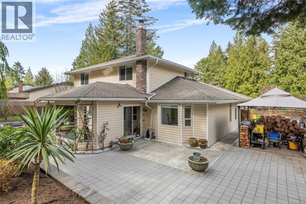 Outdoor patio area with wicker furniture, dining set, and stone retaining wall. - 1170 Clubhouse Dr, Qualicum Beach