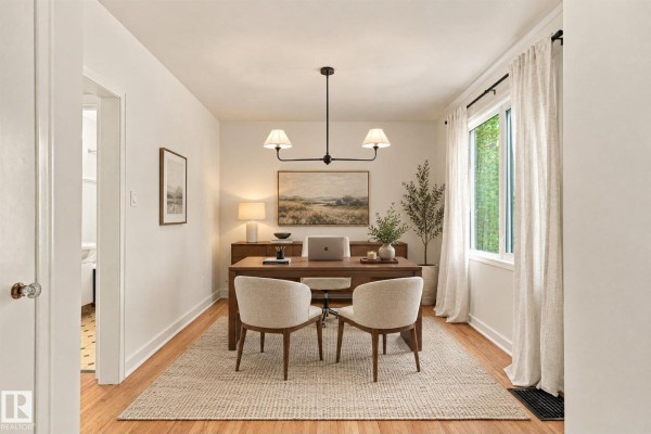 A home office with a wooden desk, chairs, rug, and artwork on a white wall. - 11718 129 St Nw, Edmonton