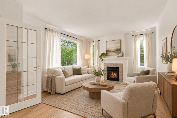Living room with a cream sofa, two armchairs, fireplace, coffee table, and glass-paneled door. - 11718 129 St Nw, Edmonton
