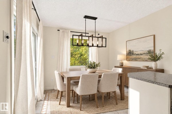 Dining room with a wooden table and chairs, chandelier, window, and sliding glass door. - 11718 129 St Nw, Edmonton