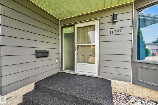 Close-up view of the front door entrance to a grey sided house with concrete steps. - 11727 27 Av Nw, Edmonton