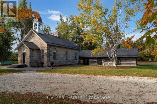 Front exterior of stone church with bell tower, black double doors, and paved walkway. - 1174 10 Nottawasaga Concession, Clearview