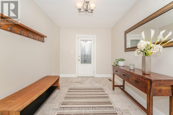 Interior foyer with tiled floor, a wooden bench, a console table with a mirror above, and a coat rack. - 1175 Kane Road, Mississauga