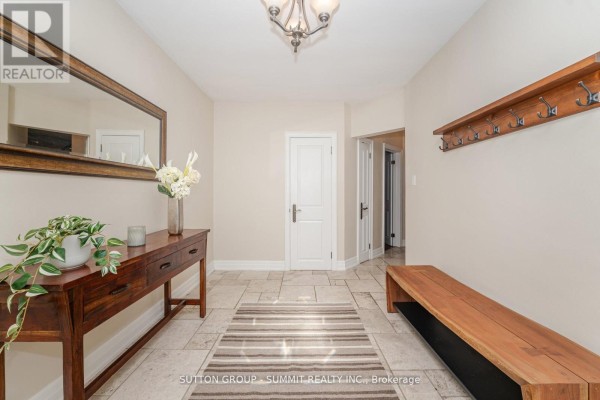 Interior foyer with tiled floor, a wooden bench, a console table with a mirror, and doors leading to other rooms. - 1175 Kane Road, Mississauga