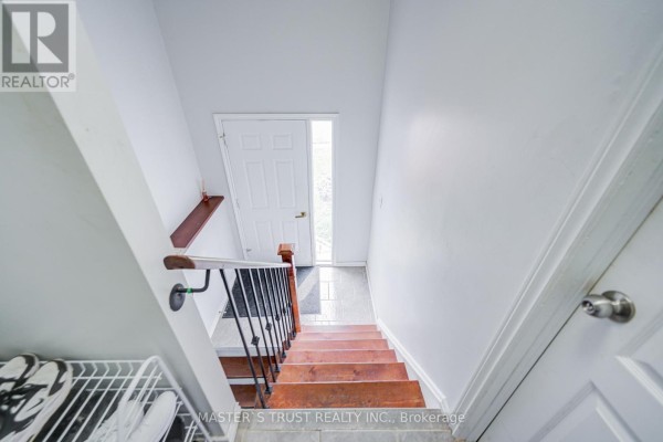 Interior view looking down wooden stairs with white walls and a white door at the bottom. - 1179 Simcoe Street S, Oshawa