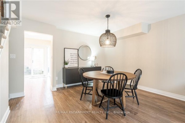 Dining room with wooden table, black chairs, sideboard, and view of staircase and hallway. - 118 - 895 Maple Avenue, Burlington