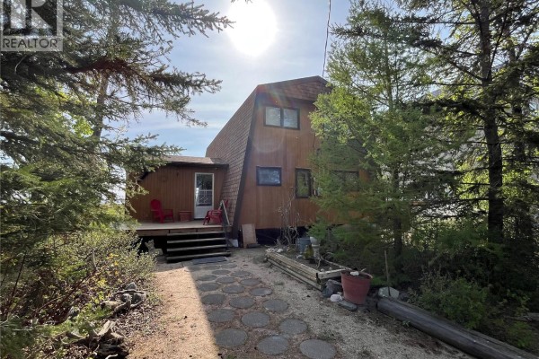 View of a-frame house exterior surrounded by trees and a stone pathway. - 118-119 Murray Crescent, Fishing Lake