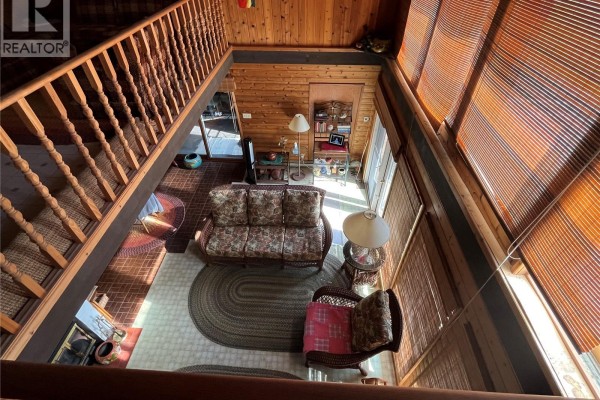 Living room with wood paneling, floral sofa, and wicker furniture seen from above. - 118-119 Murray Crescent, Fishing Lake