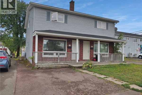 Side view of a two-unit home showing brick and grey siding construction. - 118-120 Vail Street, Moncton