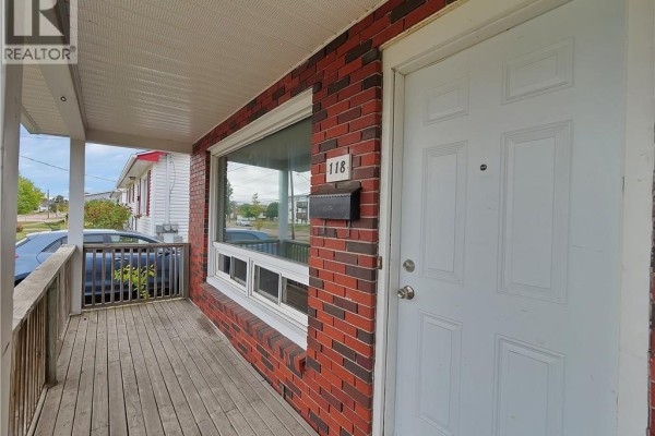 Covered front porch with wooden deck next to a white front door. - 118-120 Vail Street, Moncton