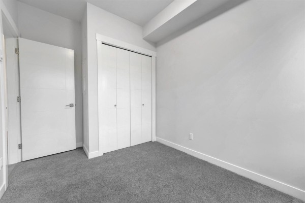 Apartment entryway with a white door, closet with shelves, and view into a bathroom. - 118 33886 Pine Street, Abbotsford