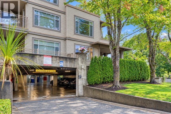 Covered parking garage entrance with concrete pillars and parked cars visible. - 118 8180 Jones Road, Richmond