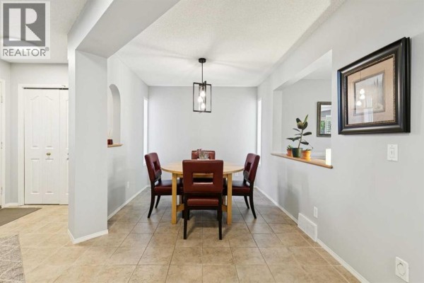 Dining room with a round wooden table, four red chairs, and light grey walls. - 118 Citadel Crest Park Nw, Calgary