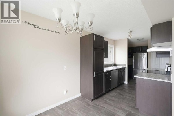 Another angle of the living room with a TV on a stand, grey sofas, and hardwood flooring. - 118 Dovertree Place Se, Calgary