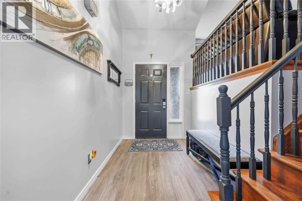 Interior entryway with light grey walls, a dark grey front door, and a wooden staircase. - 118 Finch Drive, Sarnia