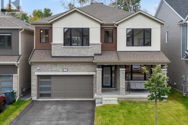 Front exterior of a modern two-story house with brick and wood siding, a double garage, and a covered porch. - 118 Green Ash Avenue, Ottawa