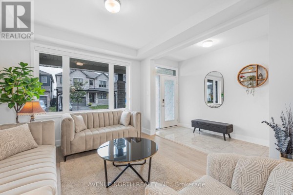 Living room with a large window, beige sofa and armchair, a black coffee table, and tiled entry. - 118 Green Ash Avenue, Ottawa