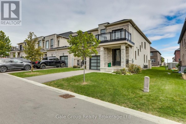 Side view of townhouse complex showing garages and lawn areas. - 118 Huntingford Trail W, Woodstock