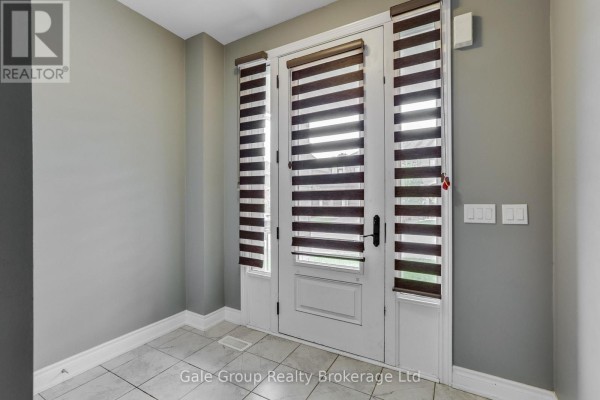 Foyer with double glass doors, white trim, and tiled floor. - 118 Huntingford Trail W, Woodstock