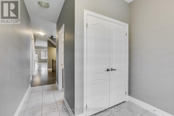 Interior hallway with tiled floor, grey walls, and double doors to a closet. - 118 Huntingford Trail W, Woodstock