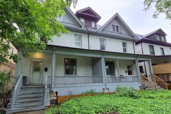 Another angle of the three-story building with snow and porch details - 118 Norquay Street, Winnipeg