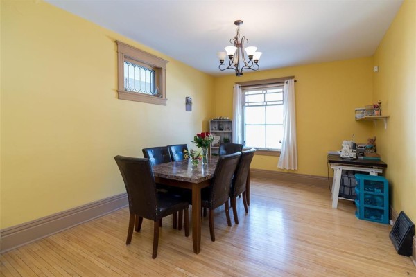 Living room featuring a black sofa, wooden floor, and exposed brick wall - 118 Norquay Street, Winnipeg