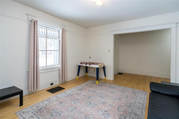 Interior view showing living room with wooden flooring and decorative door - 118 Norquay Street, Winnipeg