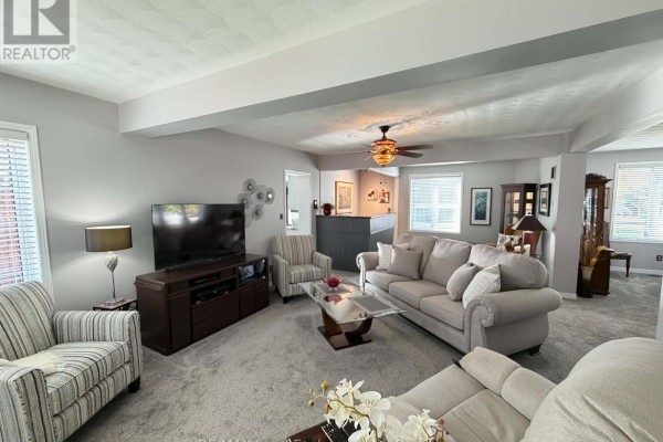 Living room with grey carpet, a sectional sofa, upholstered chairs, and a television on a media console. - 118 Victoria Street E, North Huron