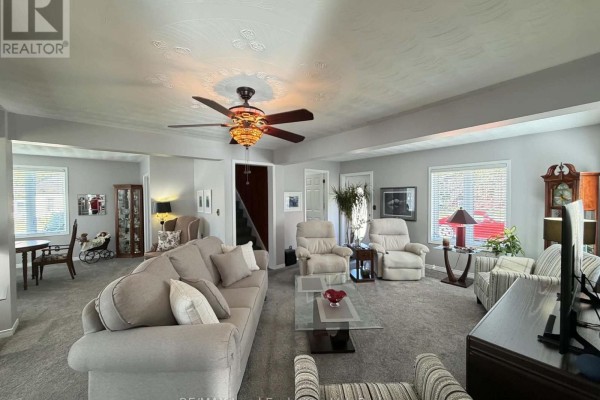 Living room with grey carpet, multiple sofas and chairs, a ceiling fan, and doorways leading to other rooms. - 118 Victoria Street E, North Huron
