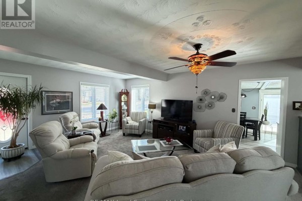Living room with grey carpet, large windows, a ceiling fan, and a view into a dining area with a table. - 118 Victoria Street E, North Huron
